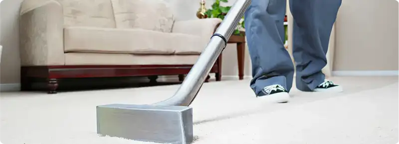 Carpet cleaning technician using a hot-water extraction wand on a light-colored carpet in a living room, Cleveland, OH.