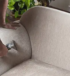 Professional upholstery cleaner deep-cleaning a fabric sofa with a handheld extraction tool and hose Cleveland, OH.